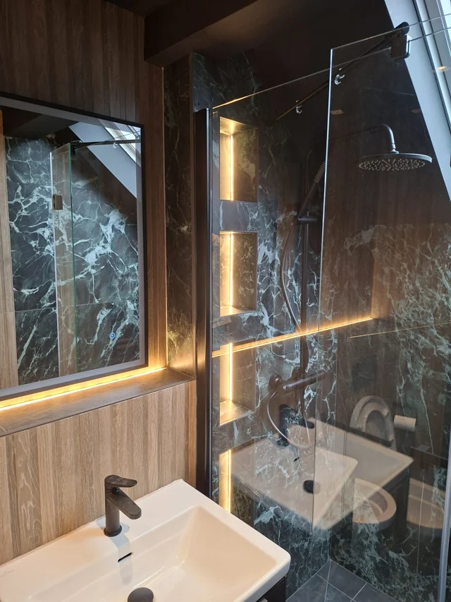Bathroom with illuminated shower niches and a light strip beneath the mirror.